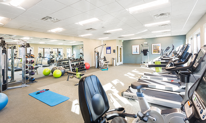 a gym with cardio equipment and weights on the floor