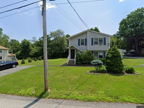 A house with a green lawn and a tree in front.