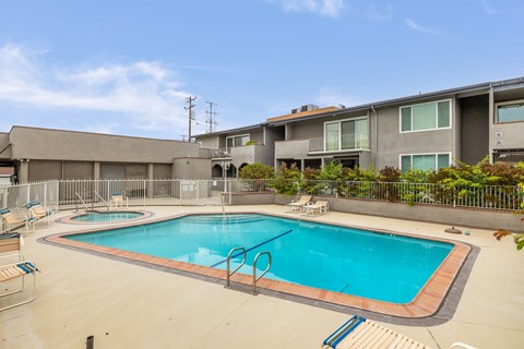A swimming pool surrounded by a fence and chairs.