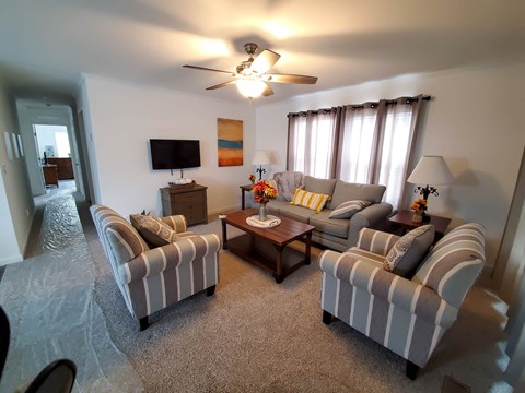A living room with a striped couch and a ceiling fan.
