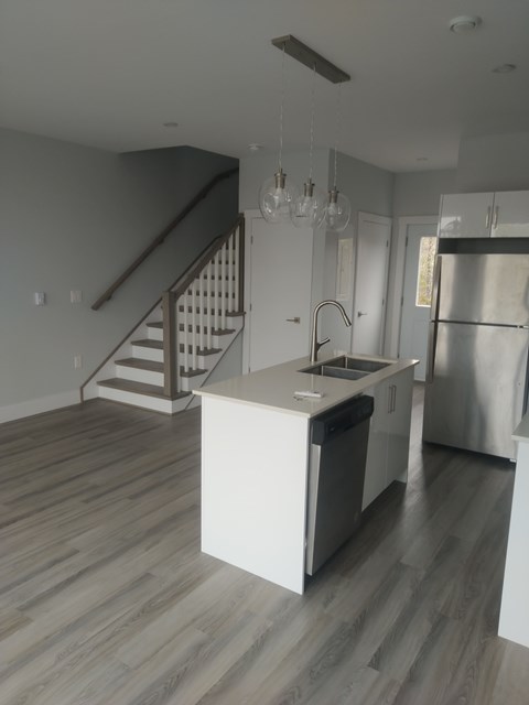 A kitchen with a staircase in the background.