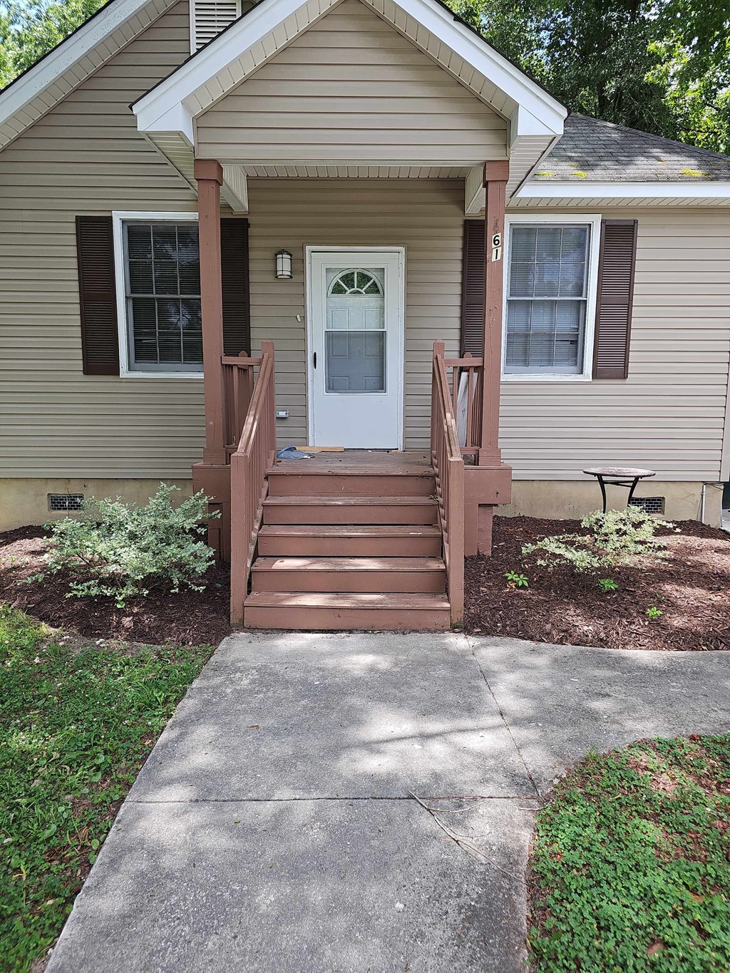A small house with a white door and a brown porch.