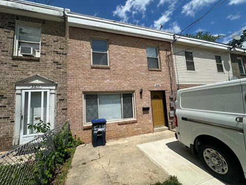 A white van is parked in front of a brick building.