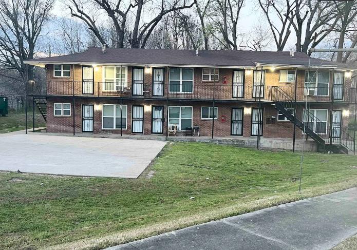 Apartment building with a parking lot in front.