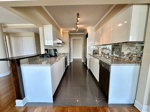 A kitchen with white cabinets and a black counter top.
