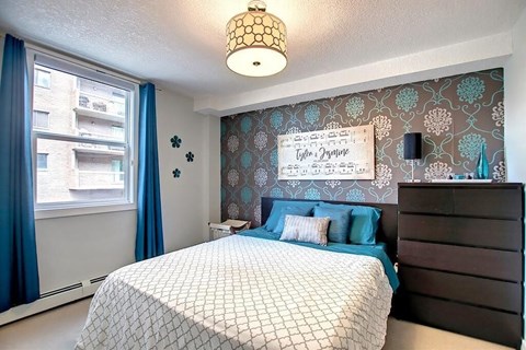 A bedroom with a bed, nightstand, and wallpaper.