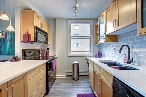 A kitchen with wooden cabinets and a black dishwasher.