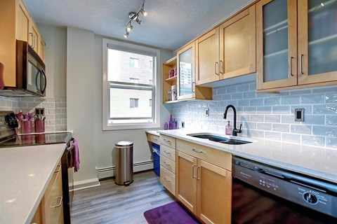 A kitchen with wooden cabinets and a stainless steel dishwasher.