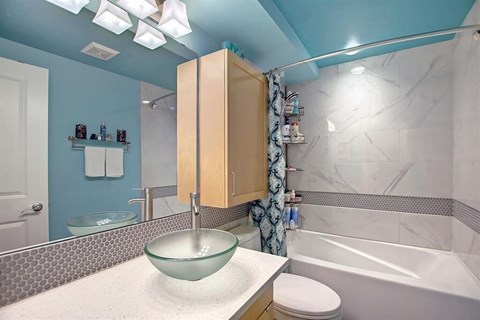 A bathroom with a blue wall and a glass bowl sink.