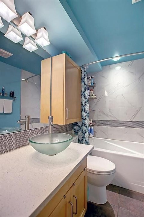 A bathroom with a white toilet and a glass bowl sink.