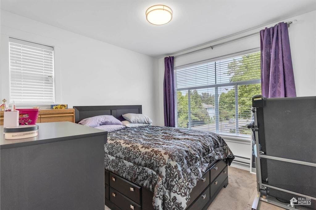 A bedroom with a bed, nightstand, and window with purple curtains.