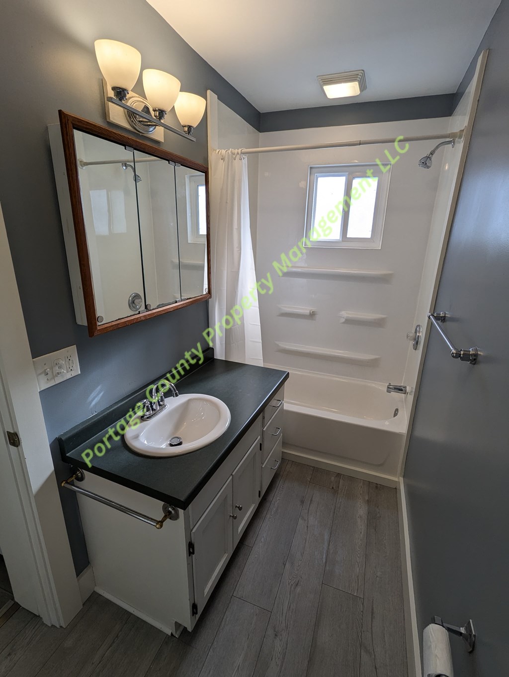 A bathroom with a sink, mirror, and bathtub.