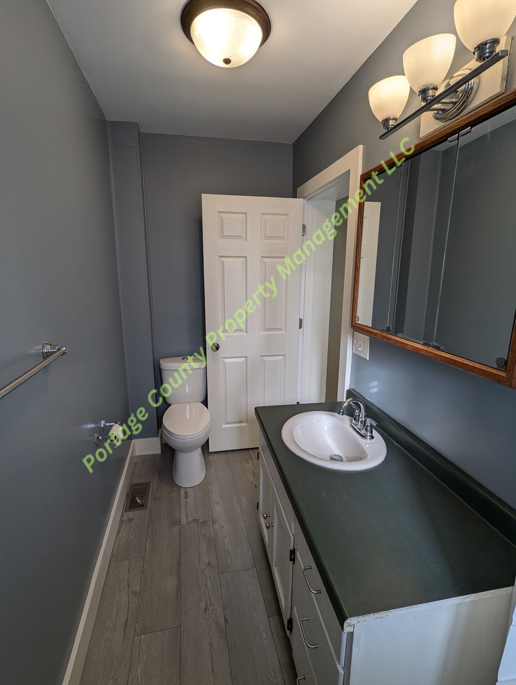 A bathroom with a sink, toilet, and mirror.