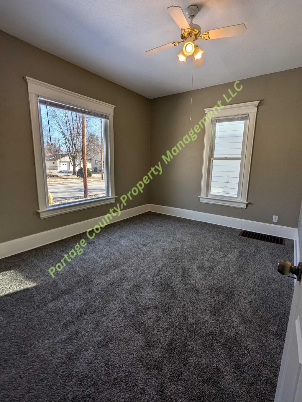 A room with a carpet floor and a ceiling fan.