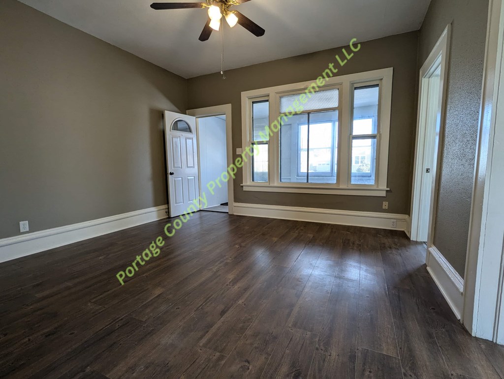A room with a ceiling fan and wooden flooring.