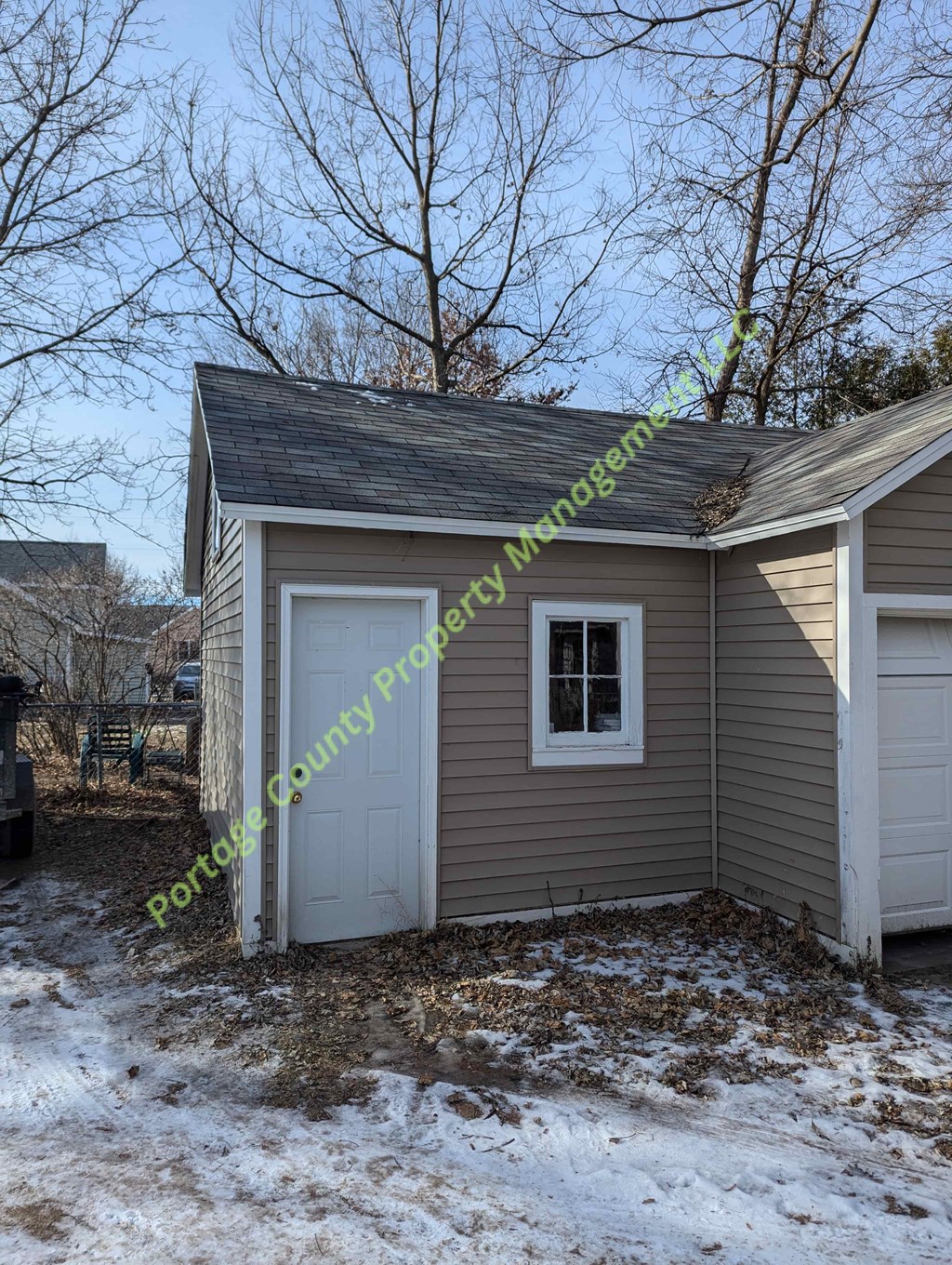 A small house with a white door and a window is surrounded by snow.