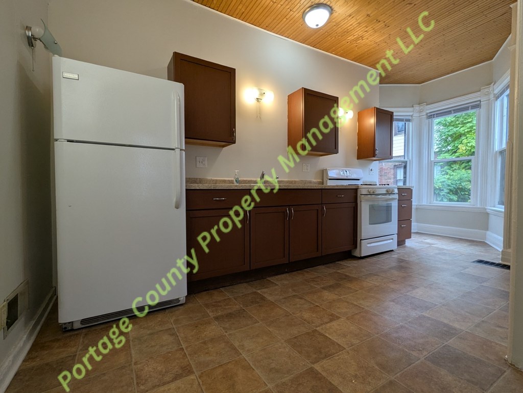 A kitchen with tile flooring and a white refrigerator.