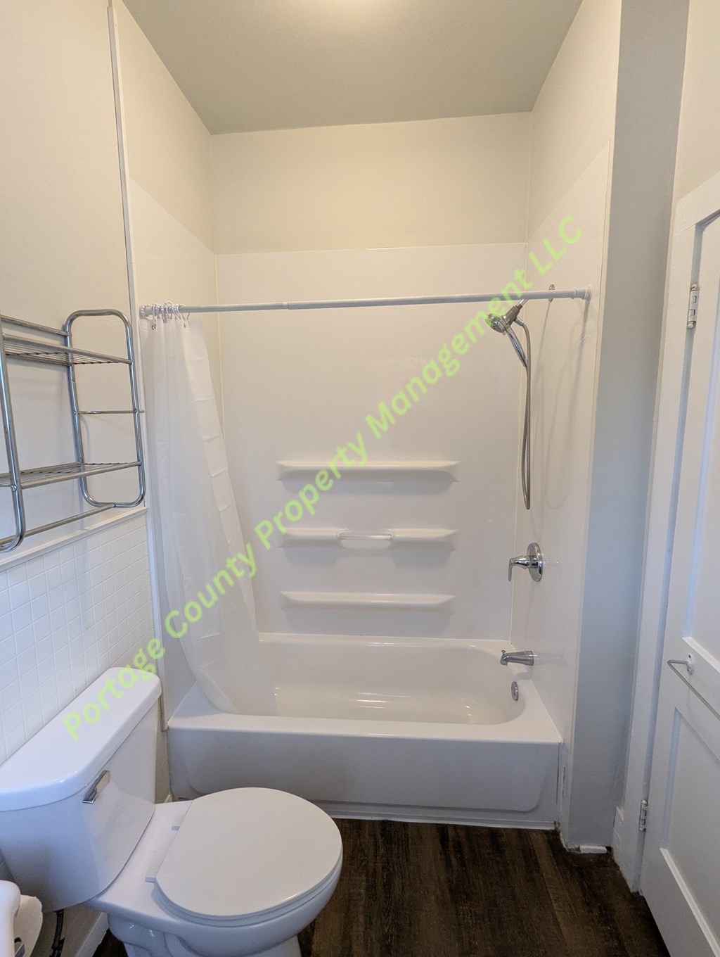 A white toilet sits next to a bathtub in a small bathroom.