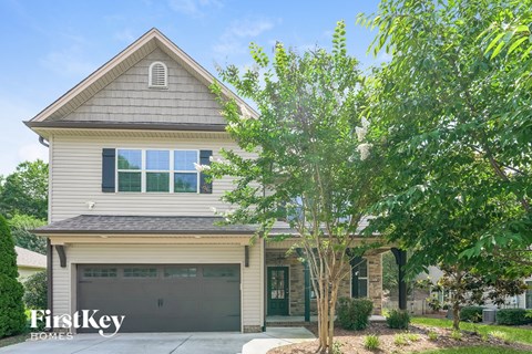 A house with a garage and a tree in front.
