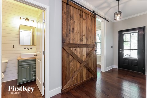 A wooden barn door in a bathroom with a green cabinet.