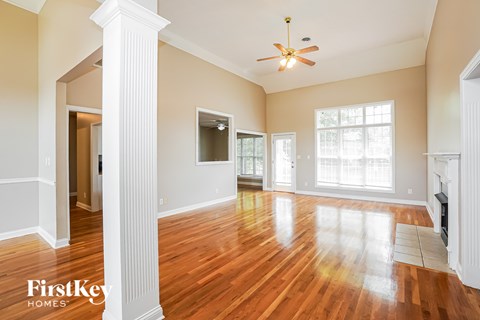 A spacious room with wooden floors and a ceiling fan.