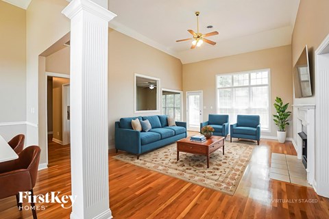 A living room with a blue couch and a ceiling fan.