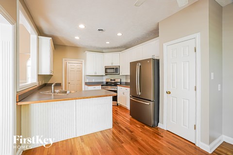 A kitchen with wooden floors and white cabinets.