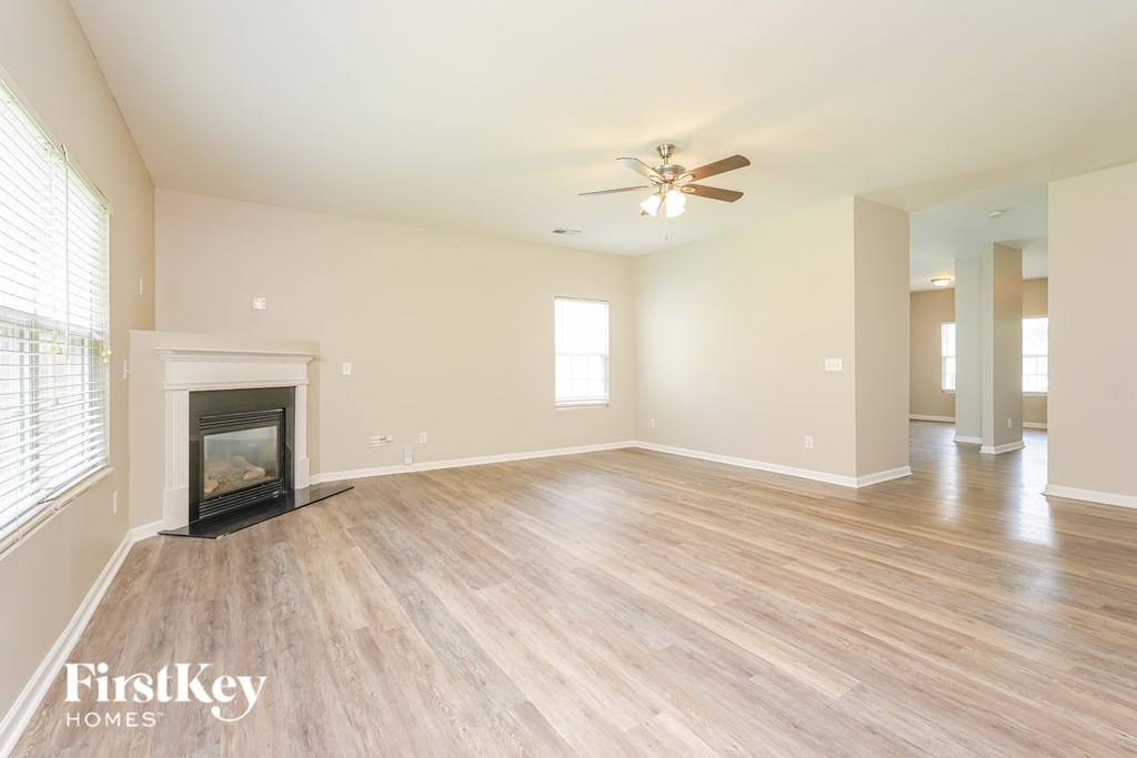 A spacious room with a fireplace and wooden flooring.