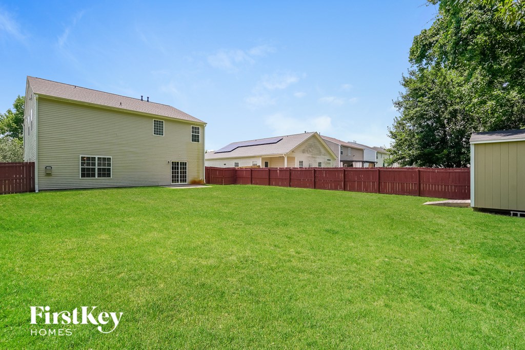 A grassy field with a barn and a house in the background.
