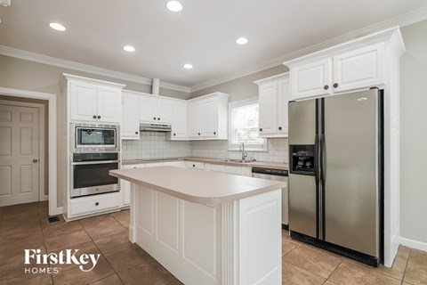 A kitchen with white cabinets and a stainless steel refrigerator.