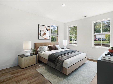 A bedroom with a large bed, a nightstand with a lamp, and a framed picture on the wall.