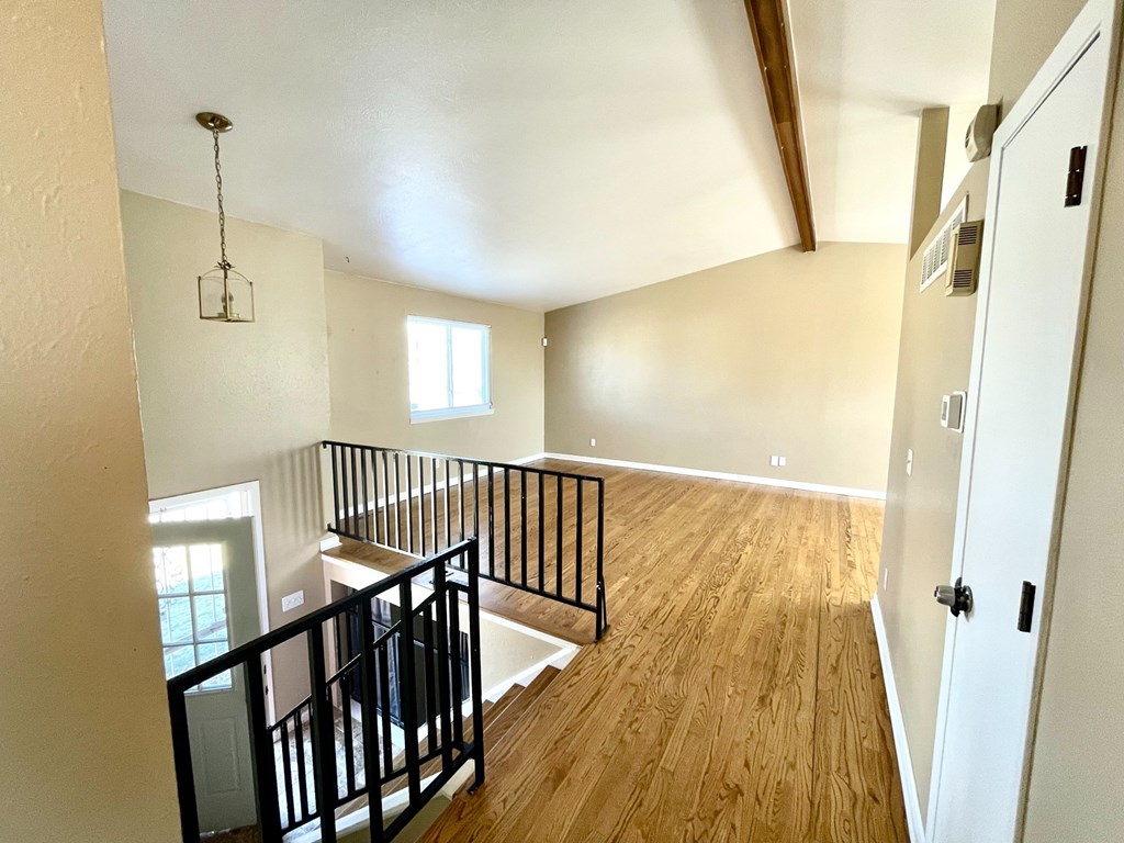 A room with wooden floors and a balcony with black railings.