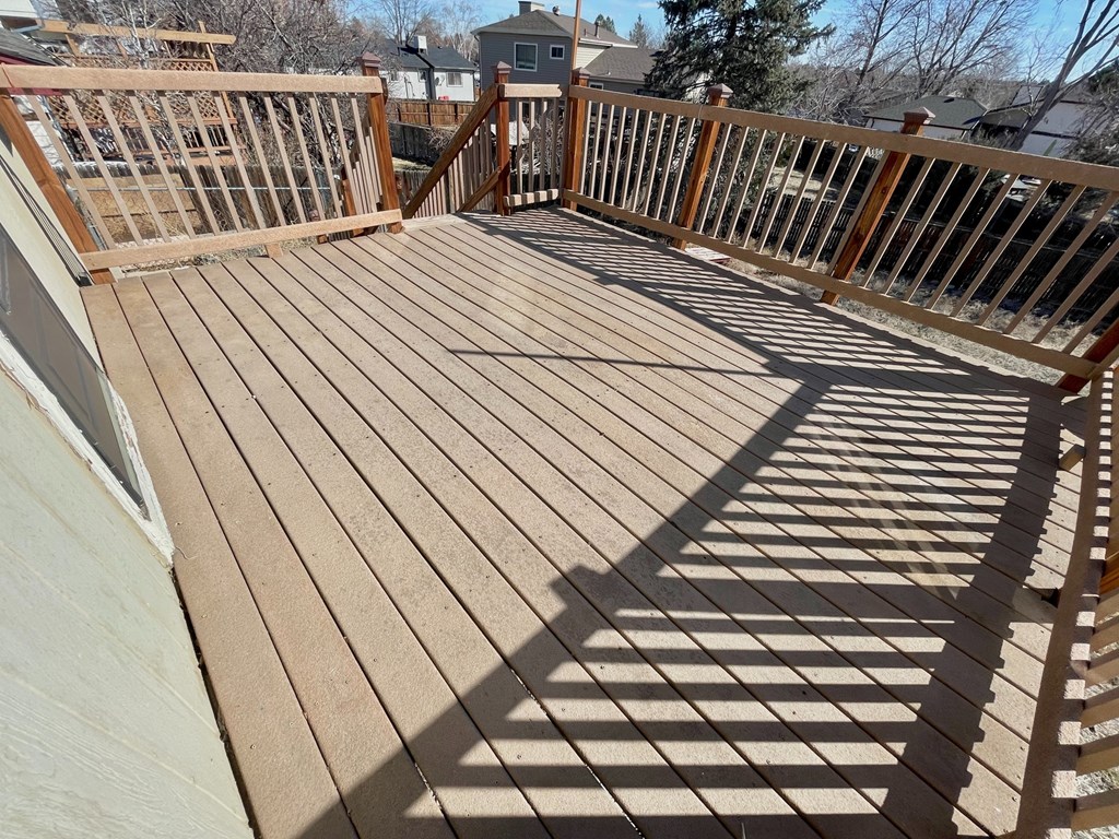 A wooden deck with a railing and a shadow cast on the floor.
