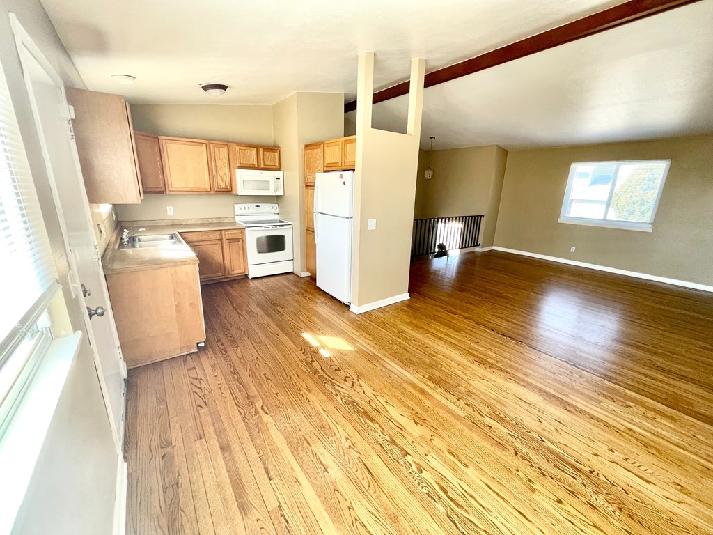 A kitchen with wooden floors and a white refrigerator.