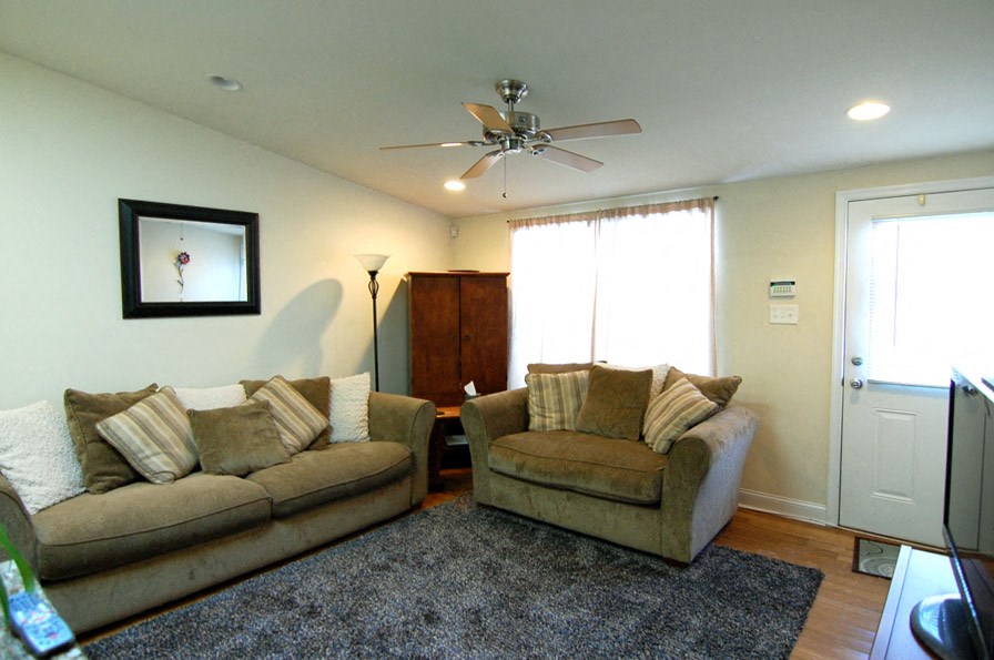 a living room with couches and a ceiling fan