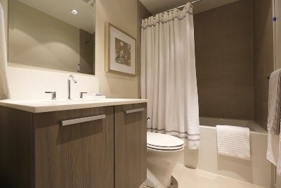 A white toilet sits in a bathroom next to a sink and a shower curtain.