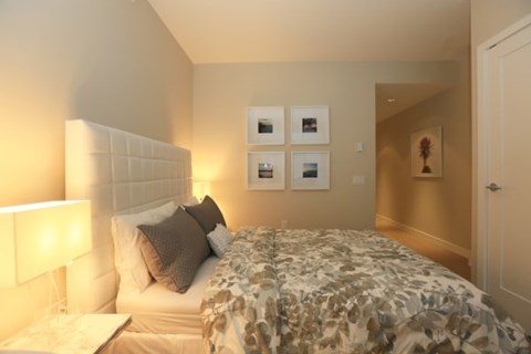 A bedroom with a bed, nightstand, and pictures on the wall.