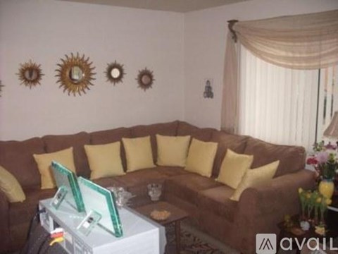 A living room with a brown couch and yellow pillows.