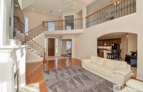A living room with a white couch and a grey rug.