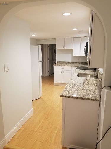 A kitchen with a granite counter top and white cabinets.