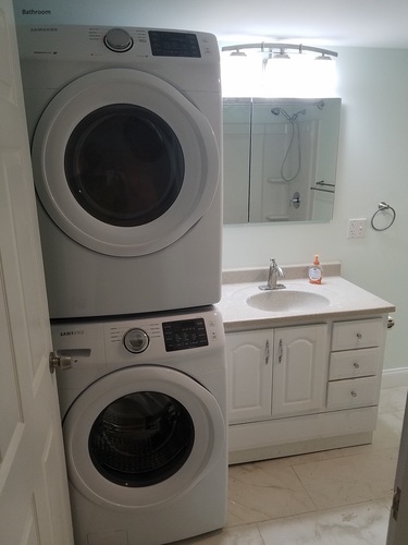 A white bathroom with a washer and dryer in the doorway.