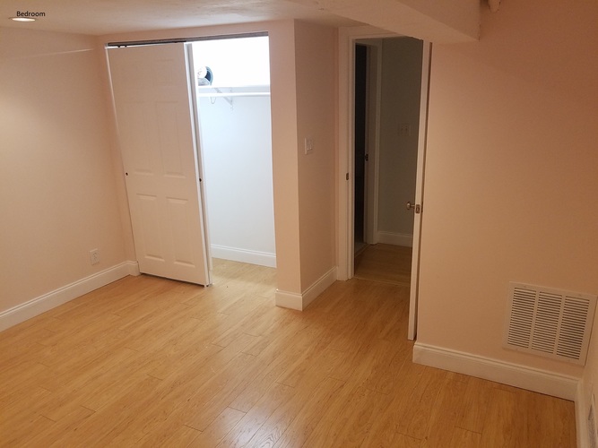 A room with a white door and a wooden floor.