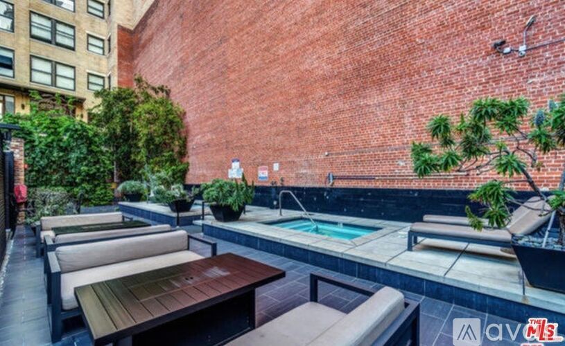 A patio with a pool and lounge chairs.