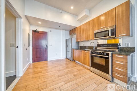 A kitchen with wooden floors and a red door.
