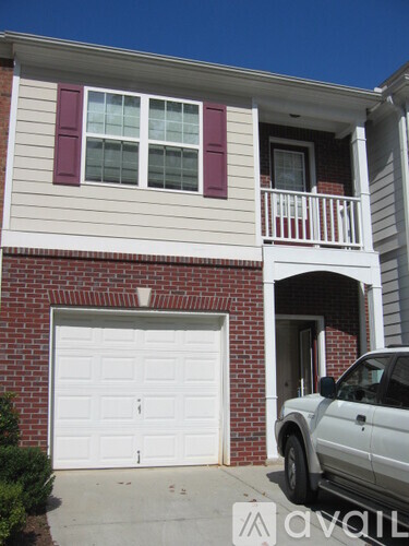 A white car is parked in front of a house with a white garage door.