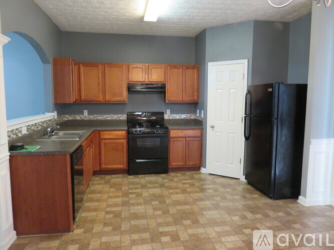 A kitchen with a black refrigerator and wooden cabinets.