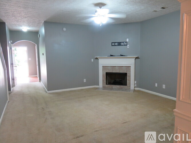 A living room with a fireplace and a ceiling fan.