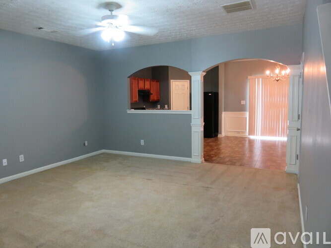 A spacious room with a ceiling fan and arched doorways.