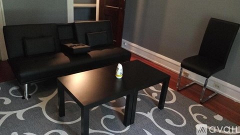 A black sofa with a table in front of it.