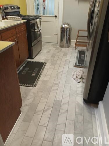 A kitchen with a black fridge and a black mat on the floor.